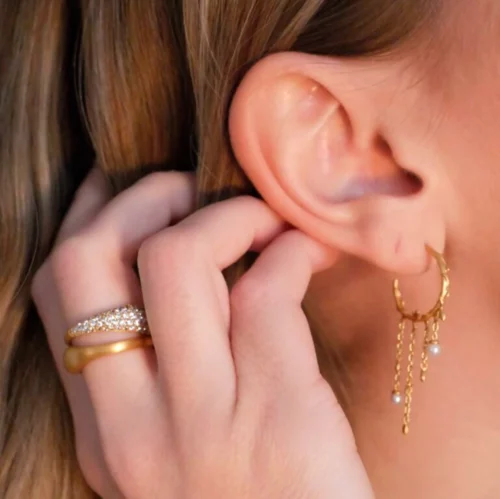 Close up of a model wearing "Jungle Ivy Hoops Pearl" and "Ocean Flow" rings