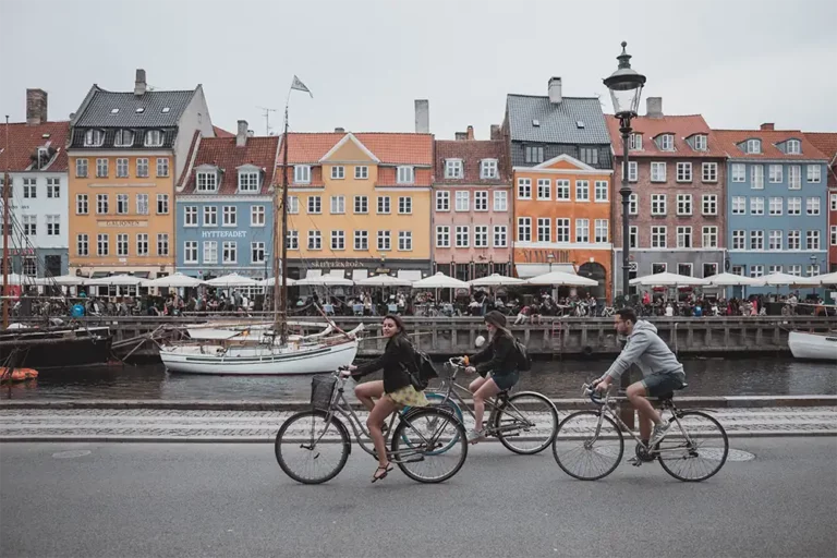 bygninger fra Nyhavn hvor 3 cykler kommer cyklende