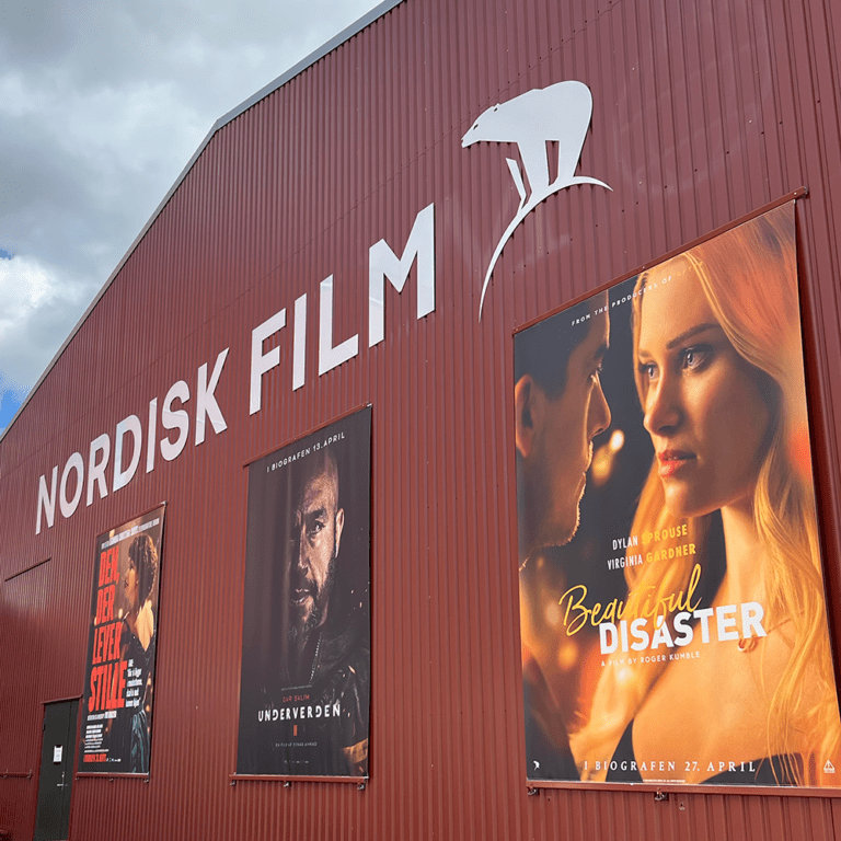 Facaden fra Nordisk Film Studier med deres logo og film plakater fra filmene Underverden 2 og Beautiful Disaster - kvadrat